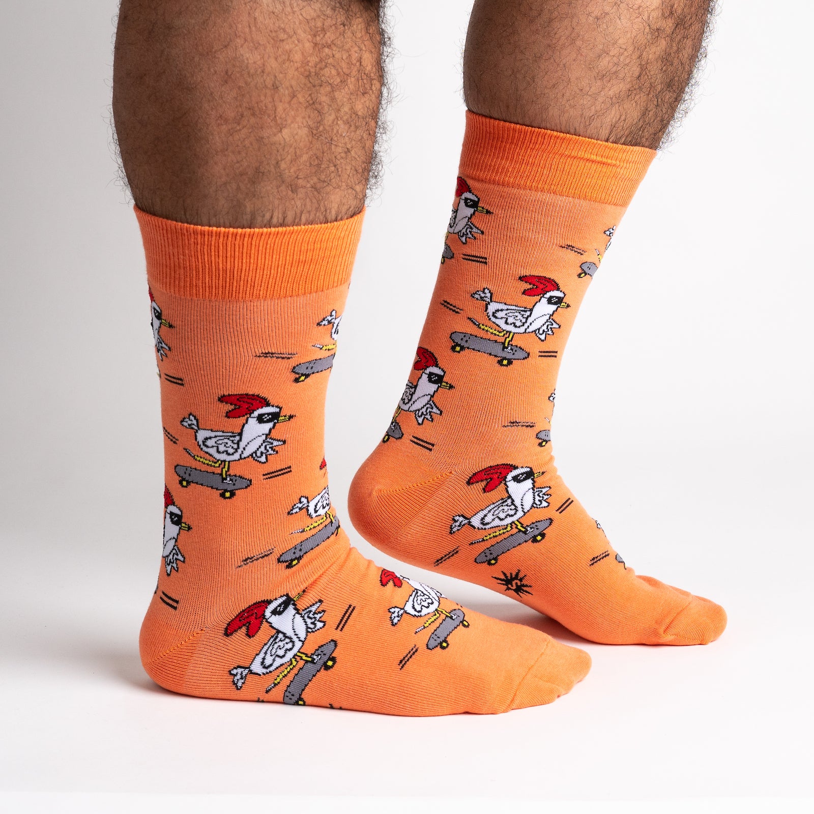 side view of model wearing rad chicken men's crew socks in orange